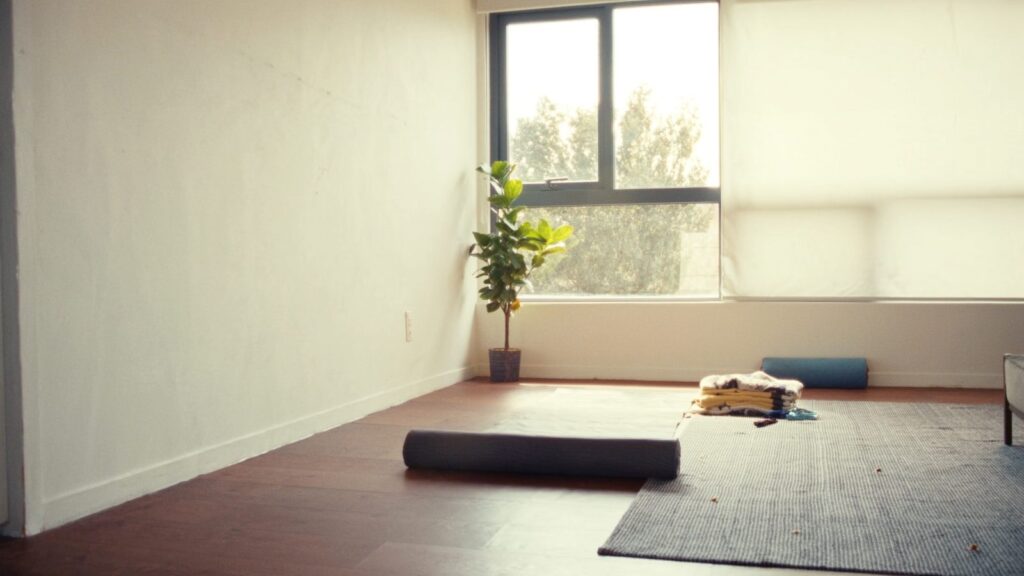 Angolo yoga in casa con tappetino, coperte e luce naturale: yoga per principianti